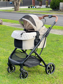 Pawbella Ultimate Pet Stroller with beige plush cushion set on a suburban lawn